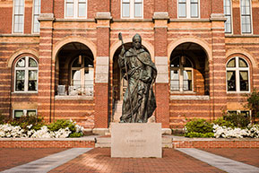 A statue of Saint Anselm sits in front of a campus building. Links to What to Give A statue of Saint Anselm sits in front of a campus building. Links to What to Give