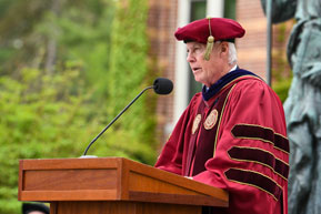 A man gives a speech to the graduating students. Links to Over Age 70
